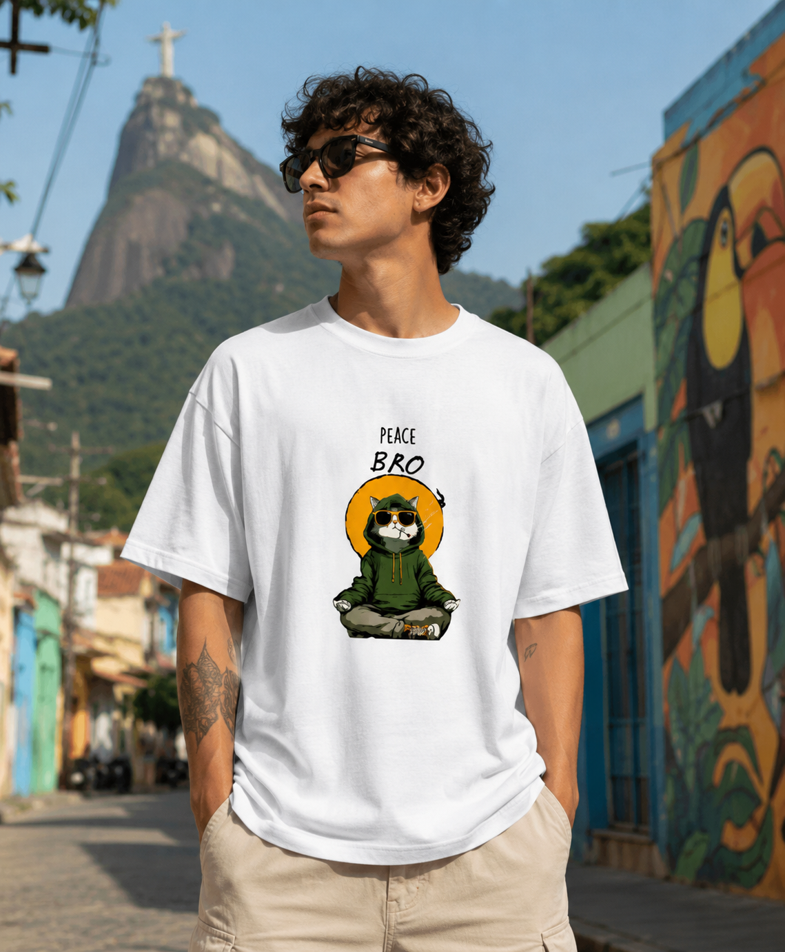Person wearing a white t-shirt with a graphic design in an urban setting with a mountain in the background