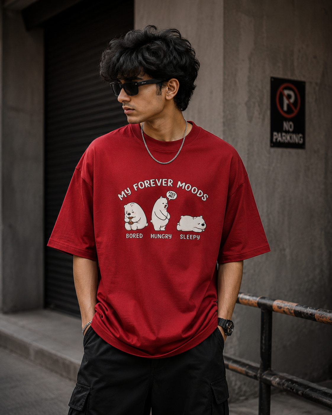 Person wearing a red t-shirt with bear graphics and text, standing against a wall.