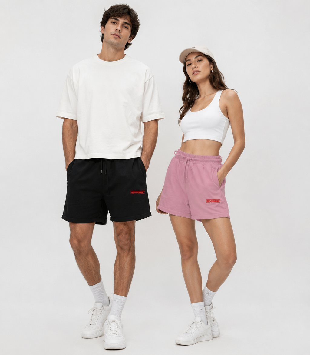 Man and woman wearing matching outfits with black shorts and pink shorts on a white background